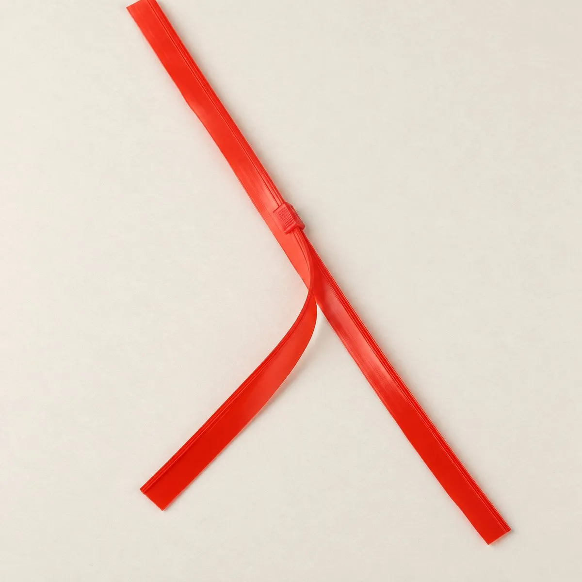 Catalogue shot of the same red zipper strip in the same V shape on a warm ground, with no tape