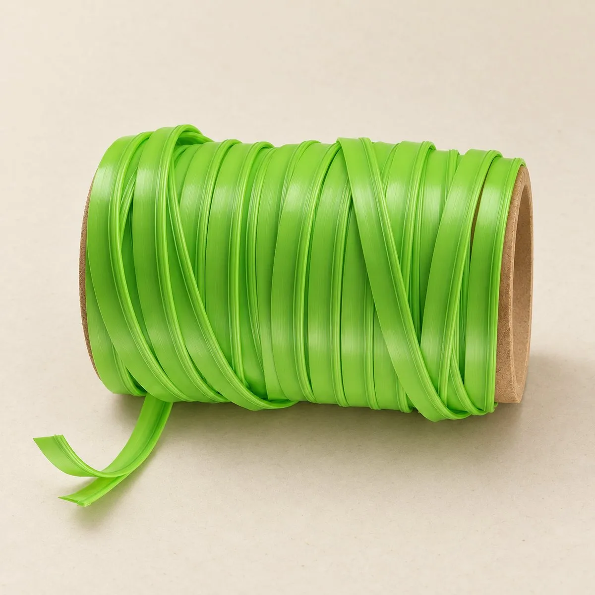 Catalogue shot of the same green zipper tape reel on a warm sand-coloured studio ground